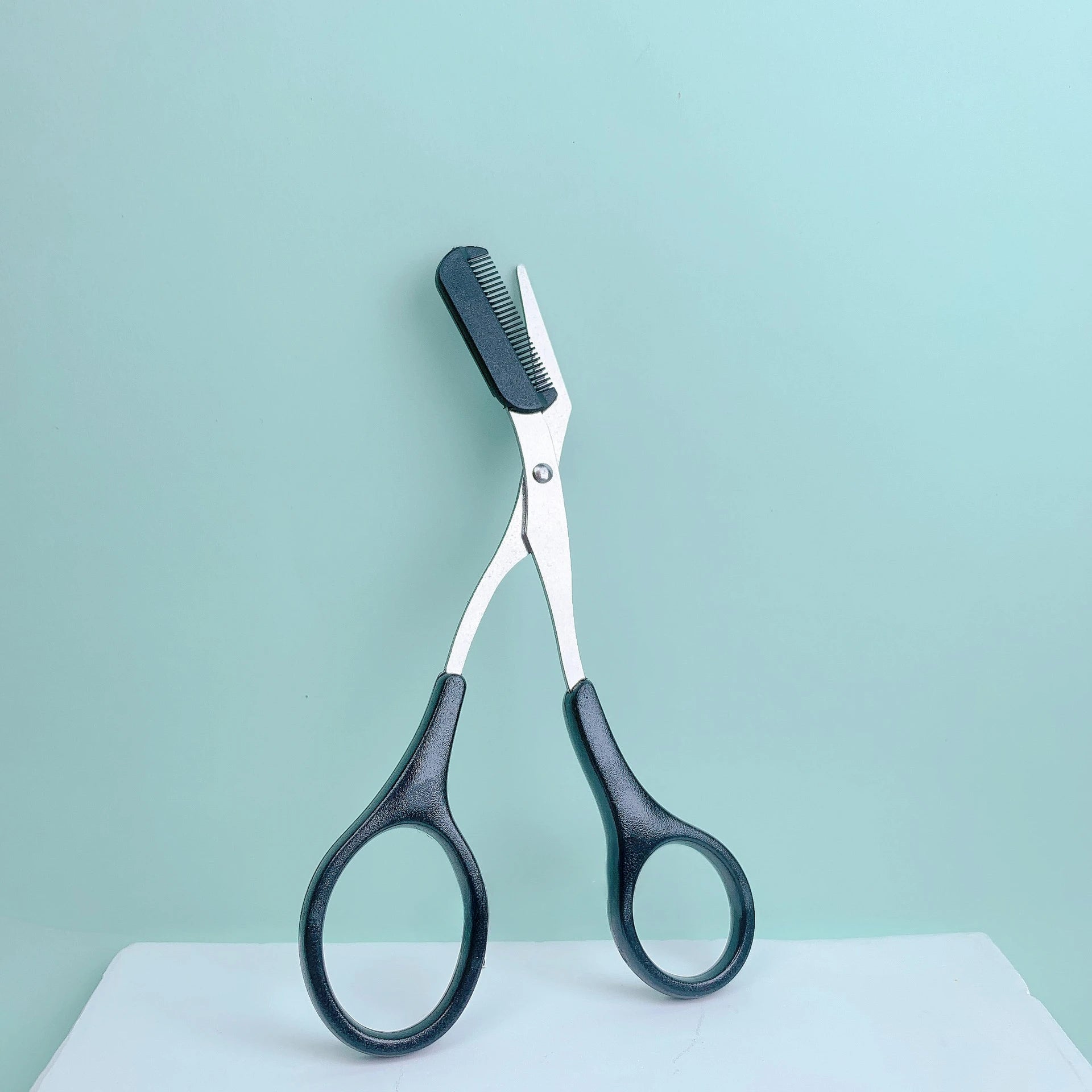 Pink eyebrow trimming scissors with built-in comb