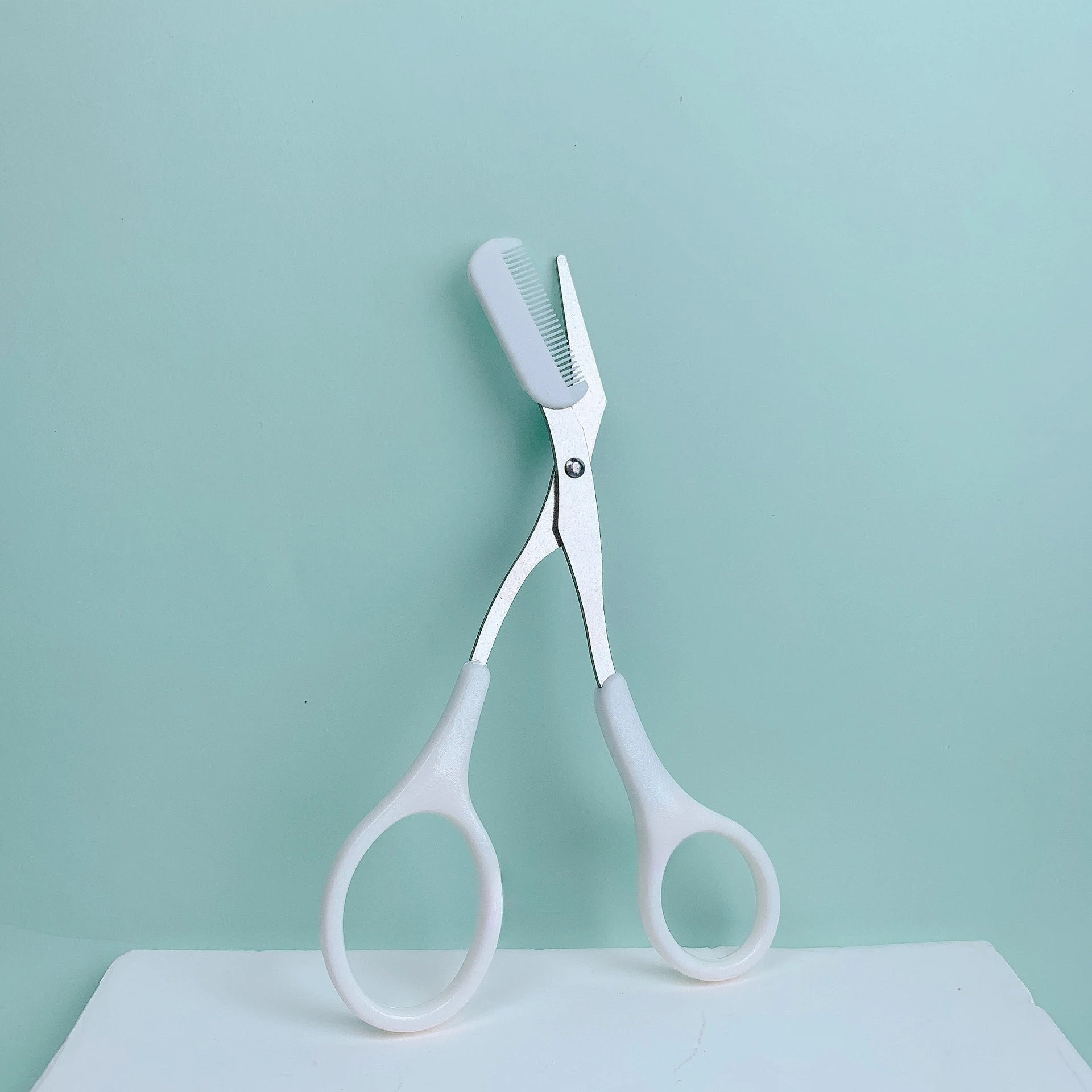 Pink eyebrow trimming scissors with built-in comb