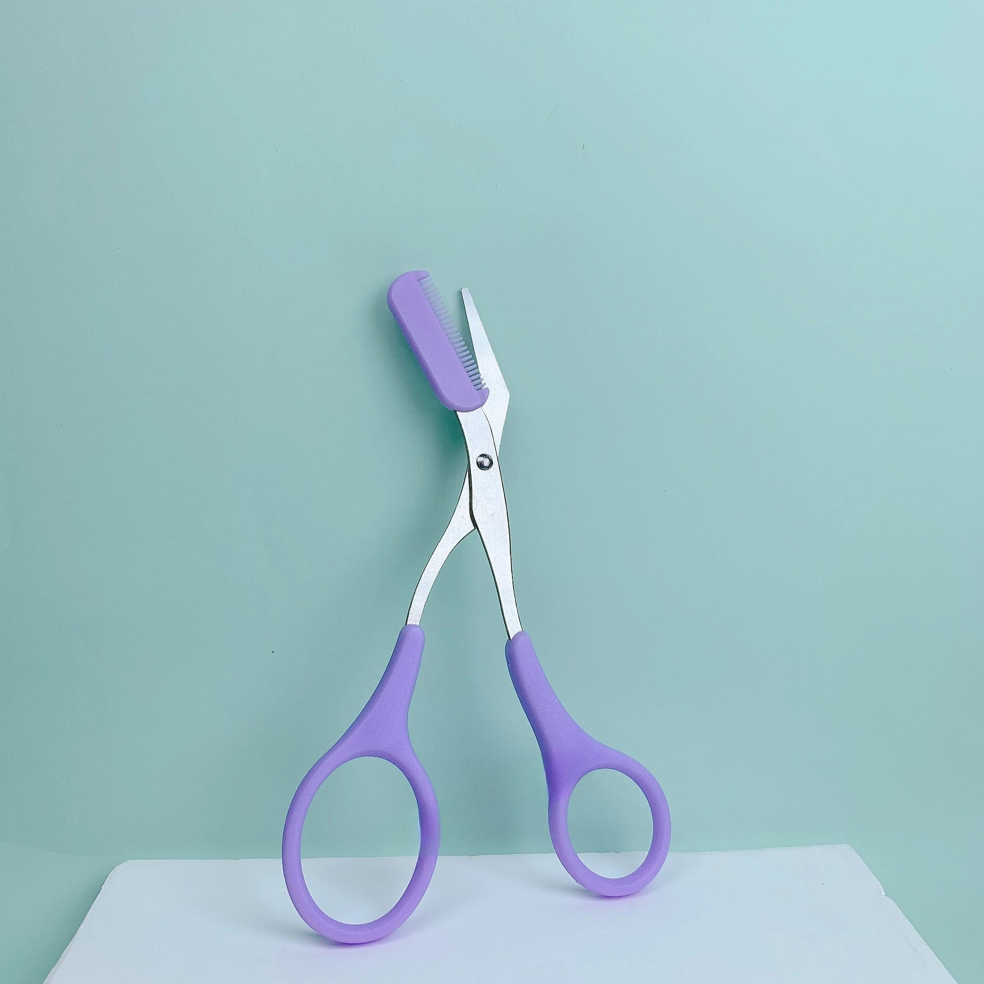 Pink eyebrow trimming scissors with built-in comb
